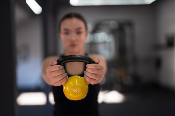 Woman using a kettlebell during a strength training session at a gym in the late afternoon