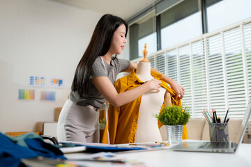 Shot of a young woman fashion designer working on a garment hanging over a mannequin.