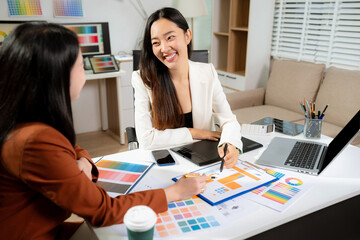 Stylish two woman designer working with digital tablet and laptop in a studio. Color, creativity in a workspace.
