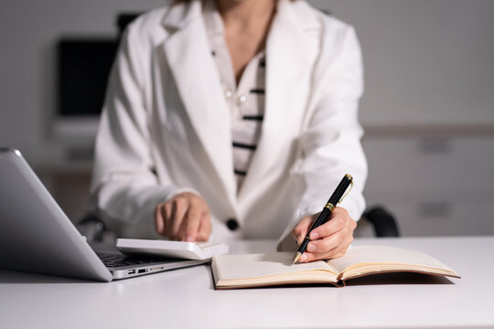 business woman working on desk office with using a calculator to calculate the numbers, finance accounting concept.