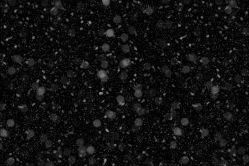 Realistic falling snow particles overlay with bokeh effect against a dark black background, creating a festive winter texture for seasonal holiday designs and motion graphics.