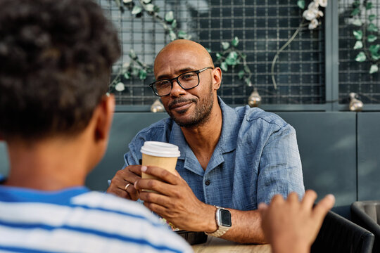 Portrait of father and son having fun outdoors in park sitting and eating during a break, family life, parenting, love and bonding concepts