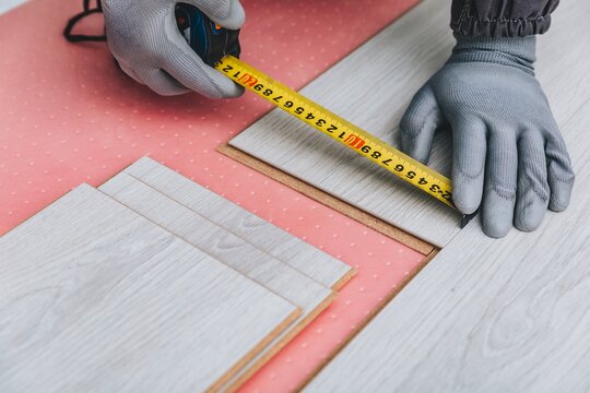 Measuring Wood Panels with a Tape Measure while Installing Flooring Materials for a Home Renovation Project