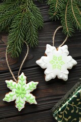 Tasty gingerbread cookies, gift box and fir tree branches on wooden table, flat lay