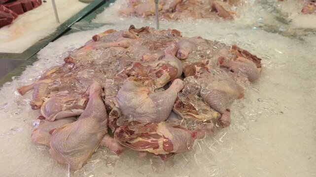 Cut chicken portions are separated and placed on ice for sale. These parts are displayed in the wet market section of a supermarket. Prices are determined by the weight and type of chicken piece.