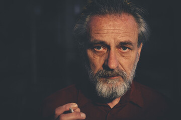 Older man in red shirt waiting for something and smoking on night city location