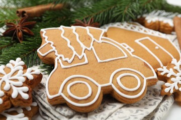 Tasty gingerbread cookies, spices and fir tree branches on white wooden table, closeup. Christmas treat