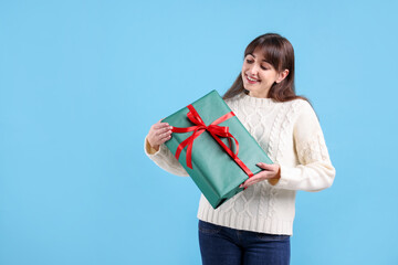 Obraz premium Smiling woman with gift box on light blue background, space for text. Christmas and New Year celebration