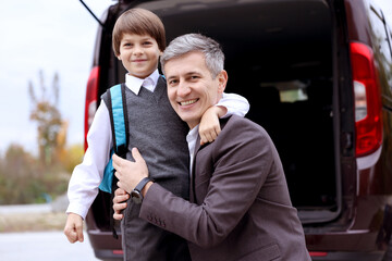Father taking his son to school near car outdoors