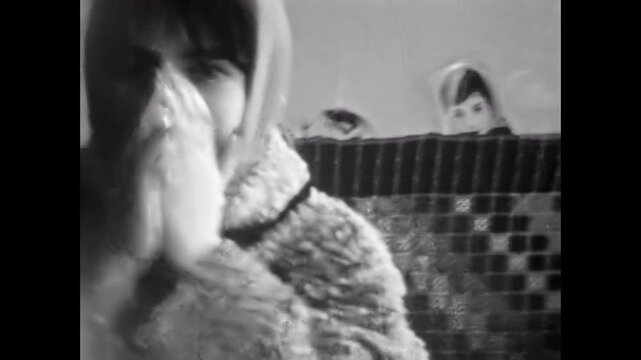 Shy girl face embarrassed to filmed, covering her face with hands, house indoor. Adorable shame smile. Young female tender expression. Blush gesture. Old film. Archival retro 1960s. Vintage archive
