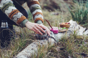 Healthy breakfast in the nature, eating home made bread and beet root pesto, drinking natural herbal tea