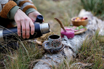 Healthy breakfast in the nature, eating home made bread and beet root pesto, drinking natural herbal tea