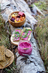 Healthy breakfast in the nature, eating home made bread and beet root pesto, drinking natural herbal tea