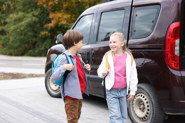Cute children with backpacks near car outdoors