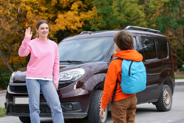 Mother taking her son to school near car outdoors
