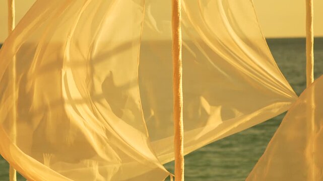 Fabric ocean gentle translucent white curtains blowing in the wind by the sea during golden hour, peaceful and serene