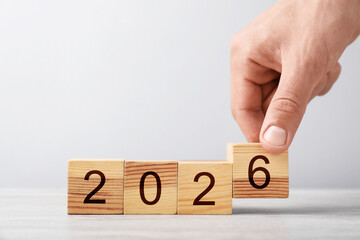 New 2026 year. Man putting cube with number 6 at white table, closeup