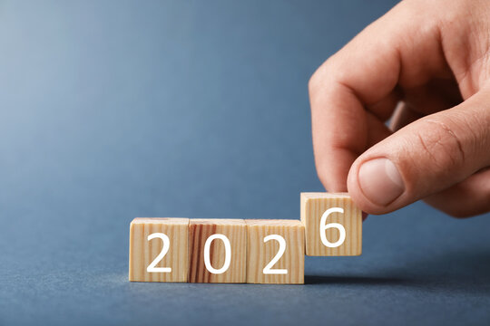 New 2026 year. Man putting cube with number 6 on grey background, closeup