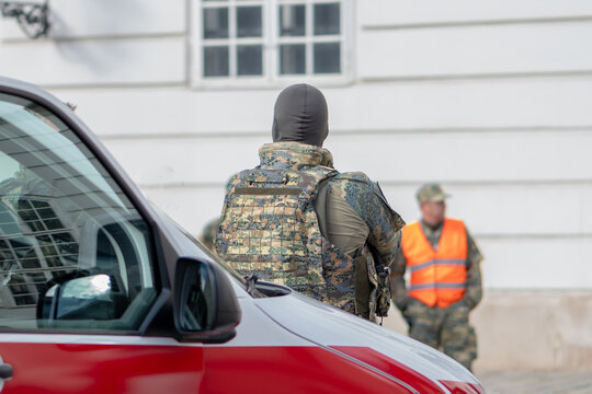 A military police officer stands next to a car in a bulletproof vest.