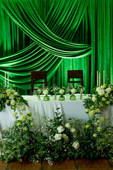 Elegant green draped wedding reception decor with floral arrangements