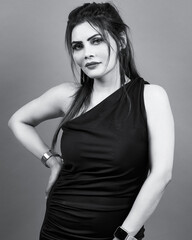 Classic black and white studio portrait of an elegant woman wearing a stylish black dress, reflecting confidence, sophistication, and modern femininity.