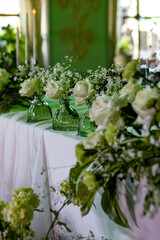 Elegant wedding table decor with white roses and greenery in glass vases