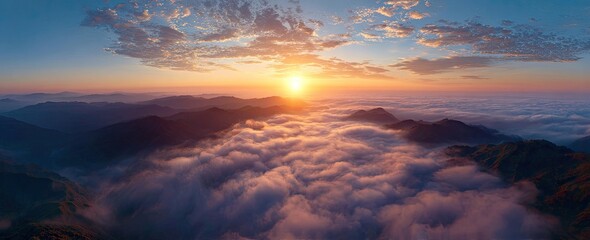 Panorama of mountain peaks piercing clouds at sunrise, sky with colorful hue