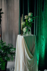 Elegant floral arrangement with white roses and candles on draped pedestal