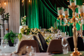 Elegant wedding reception decor with floral arrangements and green drapes
