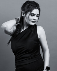 Black and white studio portrait of a confident and stylish woman wearing a one-shoulder black dress, expressing beauty, grace, and empowerment.