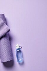 Minimalist Arrangement of Folded Lavender Towel and Water Bottle on a Smooth Lavender Background