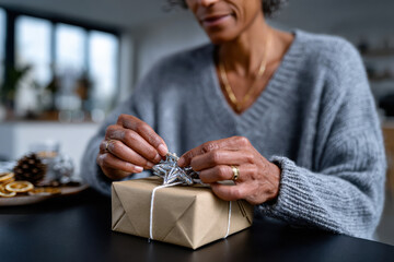 An artistic close-up of a person finishing a beautifully wrapped gift, emphasizing elegance and care, with thoughtful decoration that highlights the joy of giving during the festive season.
