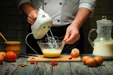 In a cozy kitchen, a chef mixes eggs and milk with an electric mixer inside a glass bowl. Fresh apples and eggs are nearby, enhancing the cooking scene
