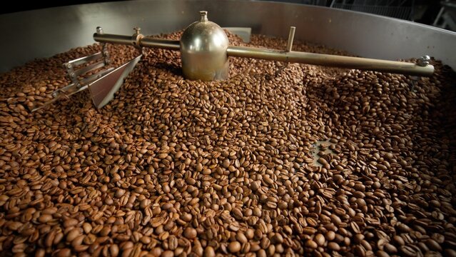 Fresh roasted coffee beans cooling in large industrial mixer machine roaster blend at modern factory aromatic brown grains blending mixing cocoa roasting closeup view of equipment production process