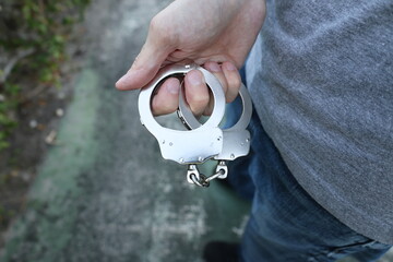 Fototapeta premium Hand holding handcuffs close up arrest concept