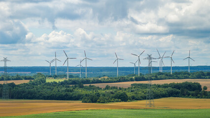 Wind farm. Windmills surrounded by high-voltage power poles. Green energy.