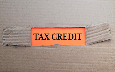 Tax Credit text on orange paper over torn card box background