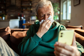 Senior man feeling sick on smartphone video call at home