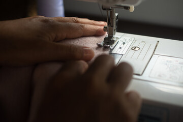An Asian mother sewing clothes with a sewing machine at home, showing love and care for her family while saving money during tough economic times. The concept of thrift, sustainable living, and simple