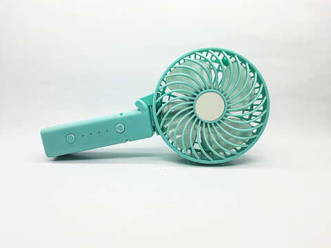 Turquoise handheld fan sits on a white background ready to provide a refreshing breeze during hot weather offering portable cooling and personal comfort for travel vacation or everyday use.