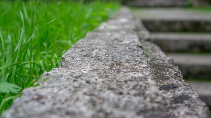 Perspective of rough stone podium table top floor on outdoors blurred grass background.