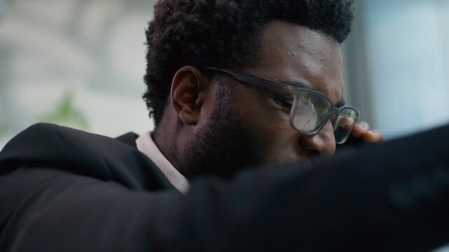 Close up furious African American man business guy male businessman in office talking mobile phone quarrel negative annoyed rage smartphone call blaming screaming talk bad negotiation communication