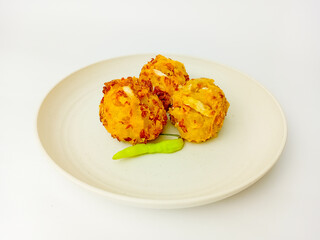 Bala-Bala or vegetable fritters with chili served on a round plate, isolated on white background.