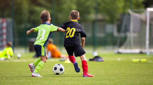 Children Playing Competitive Soccer. Youth Players in Neon Green and Black Jerseys Running Toward Soccer Ball. Kids Have Fun During Football Match - Powered by Adobe