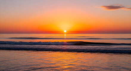 Obraz premium Breathtaking sunrise over the ocean with vibrant orange hues creating a peaceful and serene atmosphere, perfect for travel and relaxation inspiration.