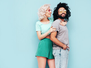 Smiling beautiful woman and her handsome boyfriend. Sexy cheerful multiracial family having tender moments on beige background in studio. Multiethnic models hugging. Embracing each other.Love concept