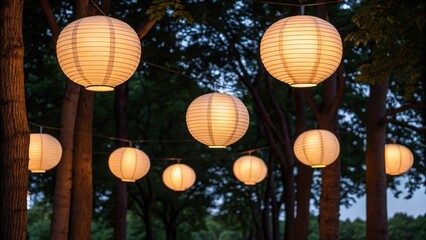 Warm glowing paper lanterns suspended between dark trees at dusk