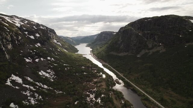 Aerial view of a long lake running between two mountains with some snow on the peaks, Dalen, Telemark, Norway.