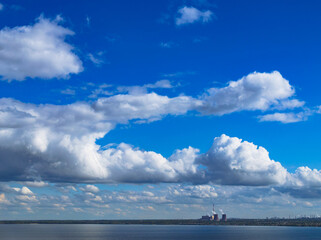 Industrial power plant by lake under blue sky