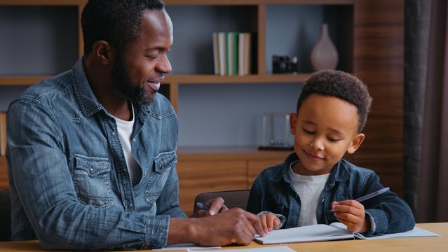African American family clever father help son writing letters write homework man teacher tutor teaching little ethnic boy kid child pupil preparing to school dad distant busy elementary education